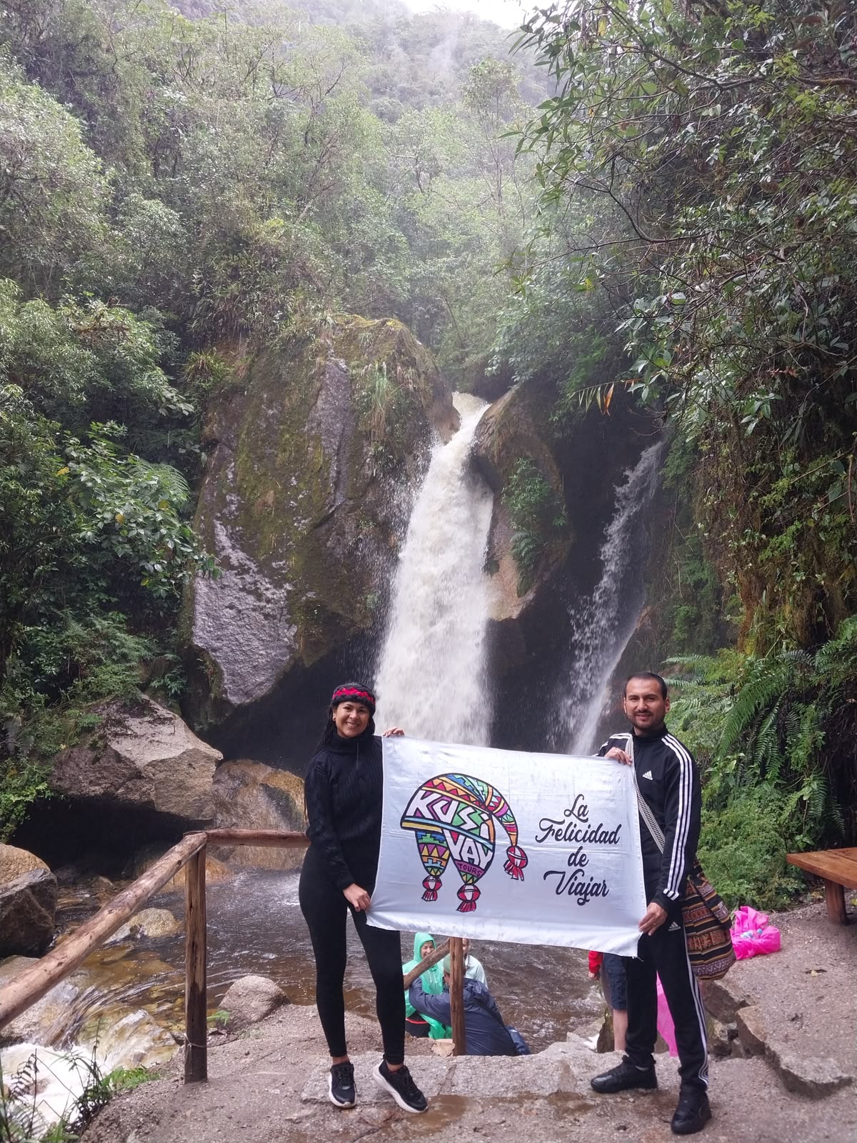 Viajeros de Kusiyay frente a una cascada en el bosque