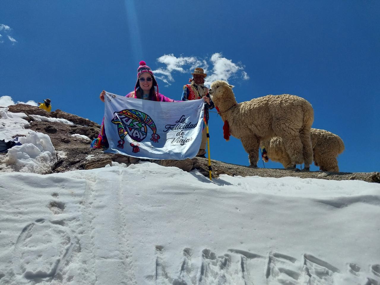 Viajera de Kusiyay junto a alpacas en un paisaje nevado