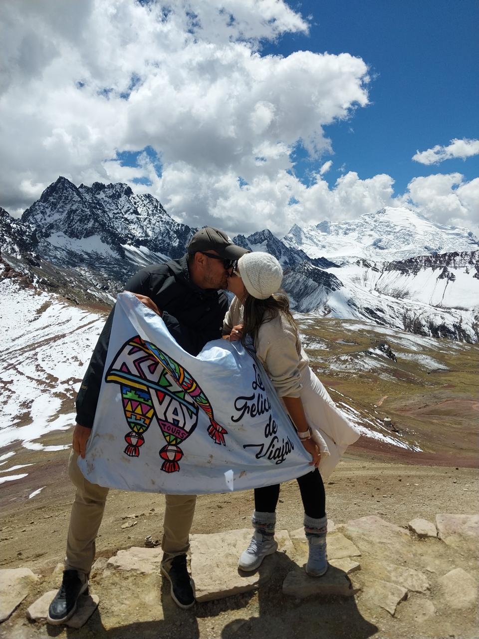 Pareja de Kusiyay con la bandera de la marca en la cordillera